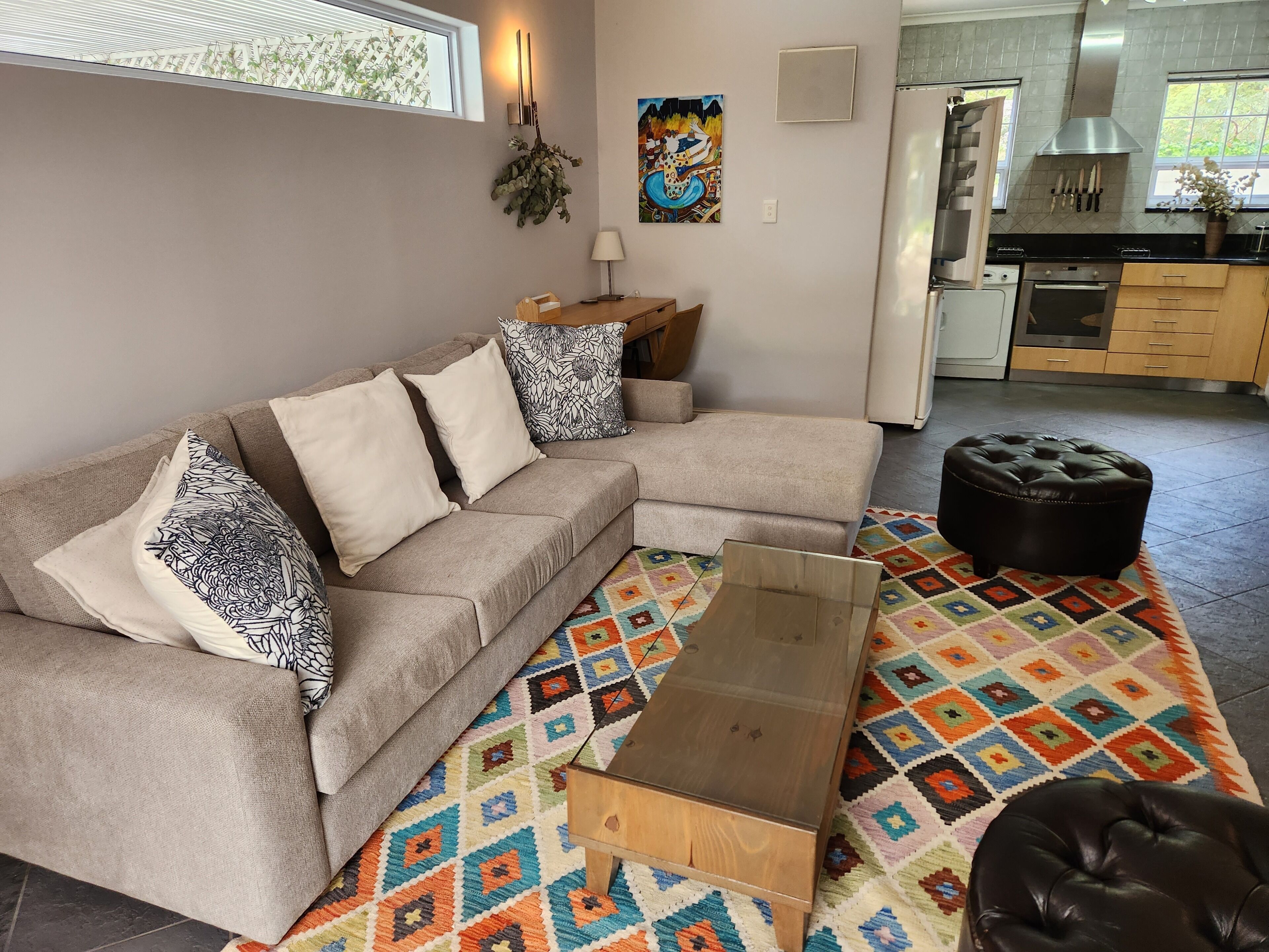 Un soggiorno moderno con un divano modulare beige, cuscini decorati, un tappeto geometrico colorato e un tavolino in legno.