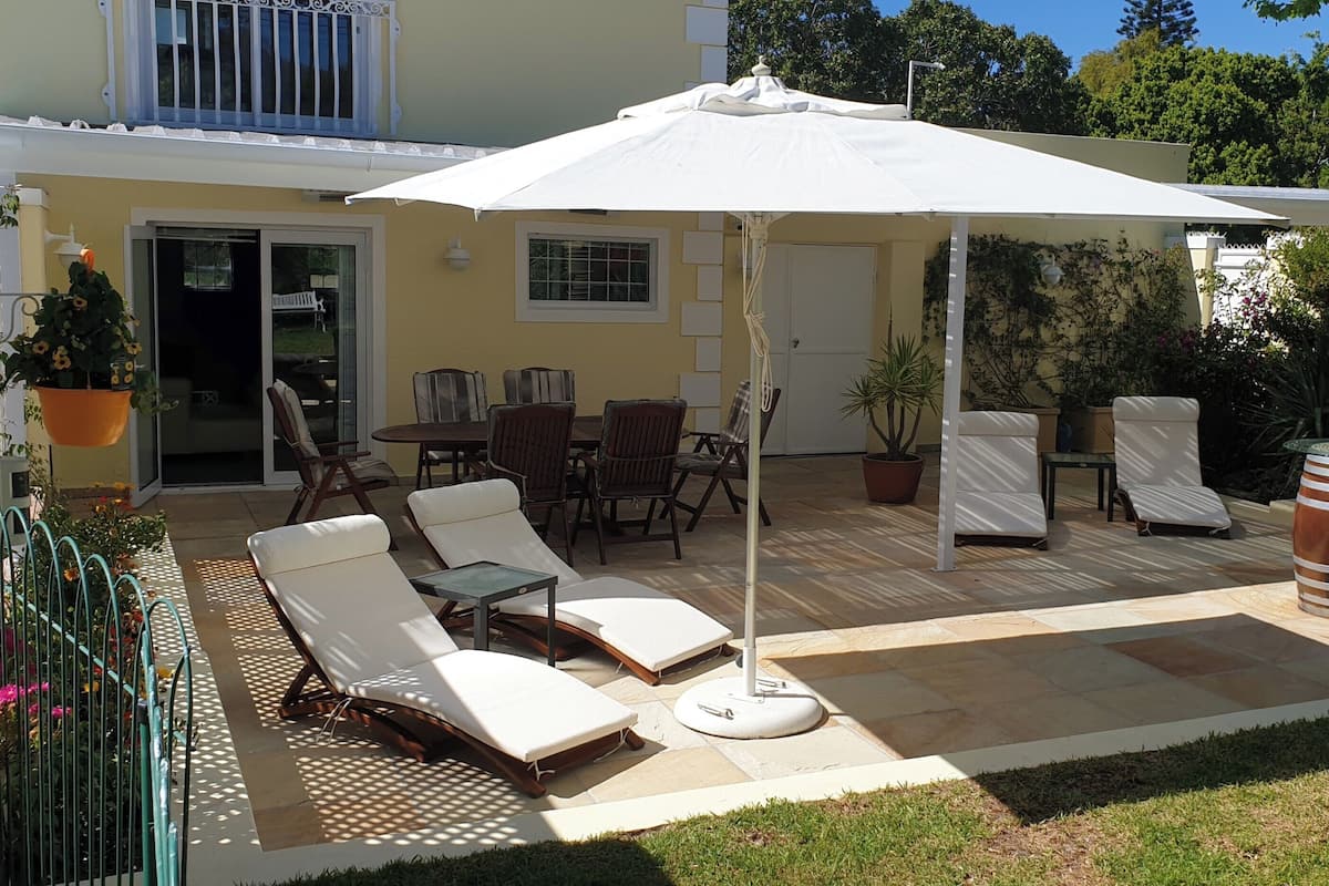 A patio with lounge chairs, a table, and a covered area with a white umbrella.