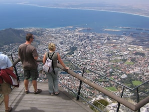A panoramic view from a high vantage point overlooking a coastal city with a mix of residential and commercial buildings.