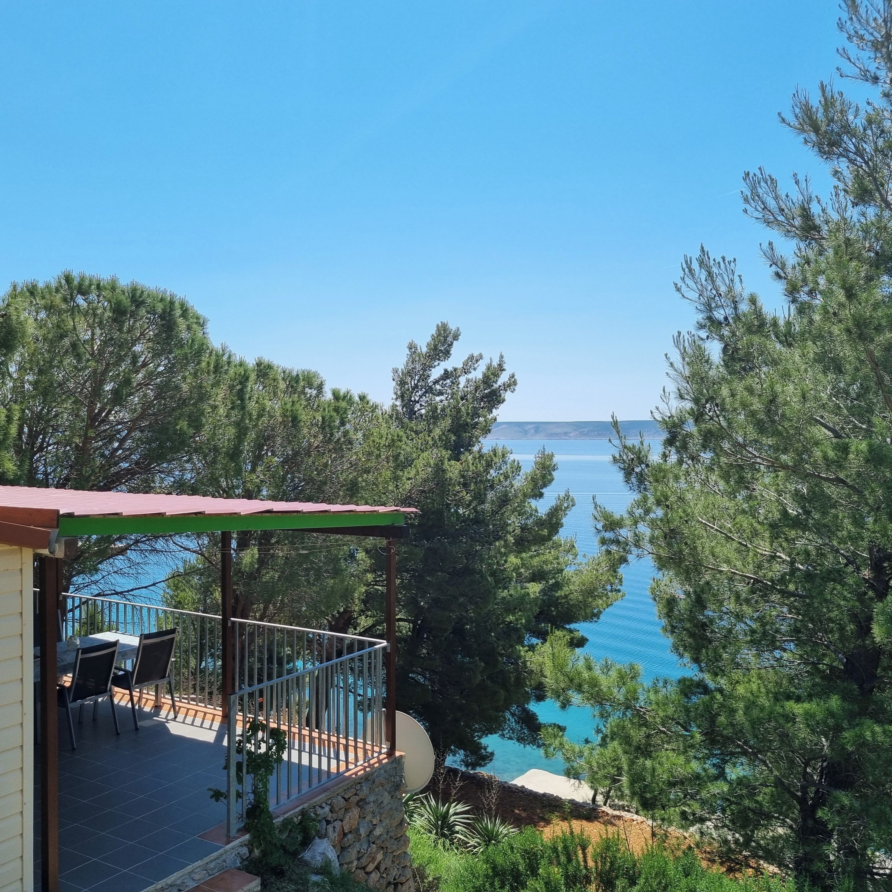 A terrace with a view of the sea, surrounded by trees.