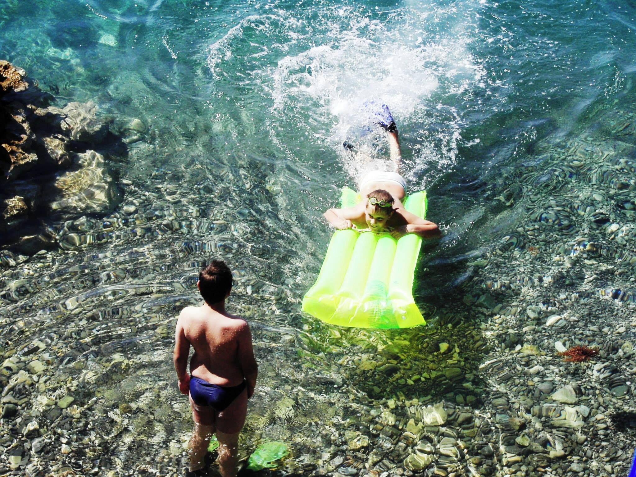 Eine Person schwimmt in klarem Wasser mit Felsen auf dem Grund.