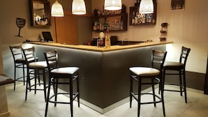 A bar area with a counter, bar stools, hanging lights, and a wine rack. - Seaside 1 BR Apartment With Balcony, up to 4 Pax (Sunny Beach)