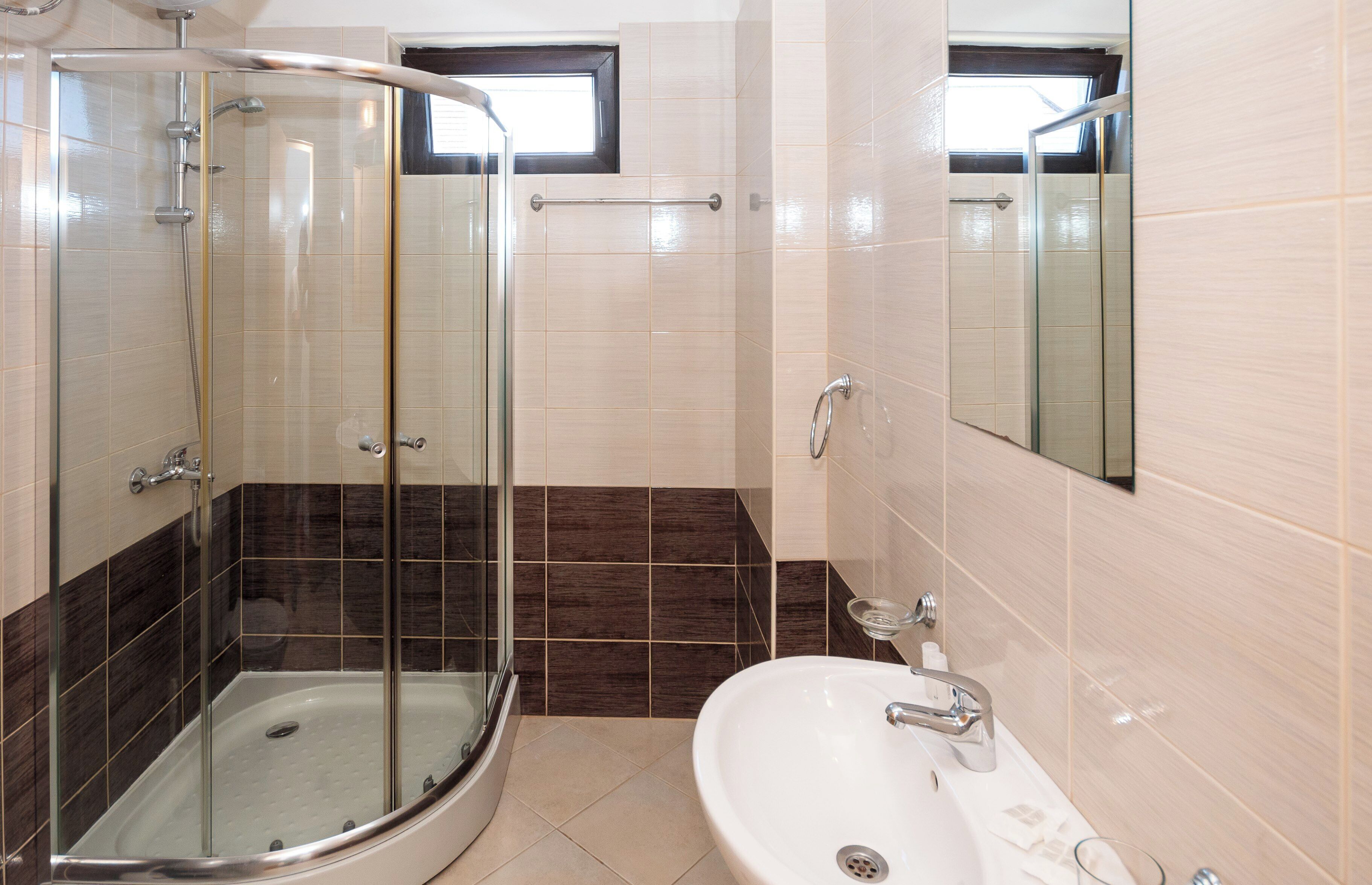 A modern bathroom with a glass-enclosed shower, a white sink, and a mirror.