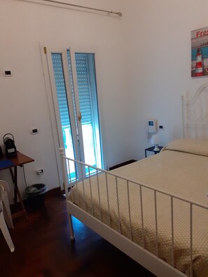 A bedroom with a bed, a small table, a chair, a window with blinds, and a poster on the wall. - Room in Guest Room - Private Room and Breakfast (Lecce)