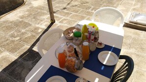 Uma mesa com diversos alimentos e bebidas, incluindo uma cesta, um pote de vidro e várias garrafas.