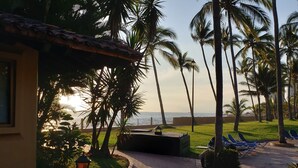 A paved pathway lined with palm trees and a view of the ocean. - Villa Facing the Beach in a Large Terrace 7 Pools, Tennis Courts, 247 Security (Puerto Vallarta)