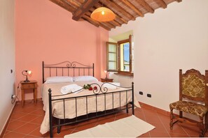 A bedroom with a bed, bedside lamps, a wooden chair, and a window. - Casa Sofi (Monticiano)