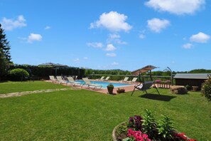 A backyard with a swimming pool, lounge chairs, and a garden. - Casa Sofi (Monticiano)