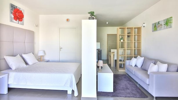 Una habitación de hotel moderna con una cama grande, un sofá, un escritorio y una estantería.