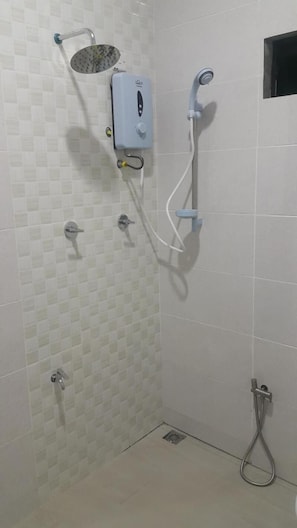 En duschplats med ett handhållet duschmunstycke, ett väggmonterat duschmunstycke och en kontrollpanel.