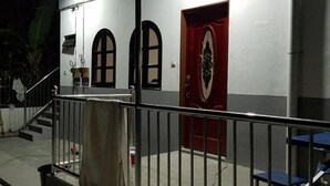 Ein Gebäude mit überdachter Eingangspartei, einer Treppe und einer roten Tür mit einem dekorativen Wappen.