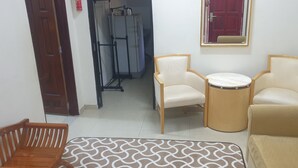 A room with a sofa, two armchairs, a small table, and a patterned rug.