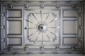 Un soffitto con un lampadario centrale e modanature elaborate.