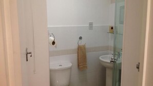 Un baño con inodoro, lavamanos y cabina de ducha de vidrio.