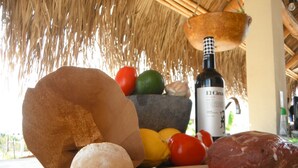 A table with a bottle of El Circo wine, a loaf of bread, a bowl of fruit, and a piece of meat.