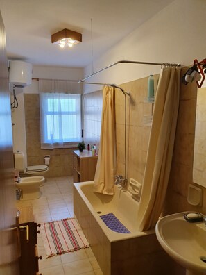 Ein Badezimmer mit einer Badewanne, Toilette, Waschbecken und Duschbereich.