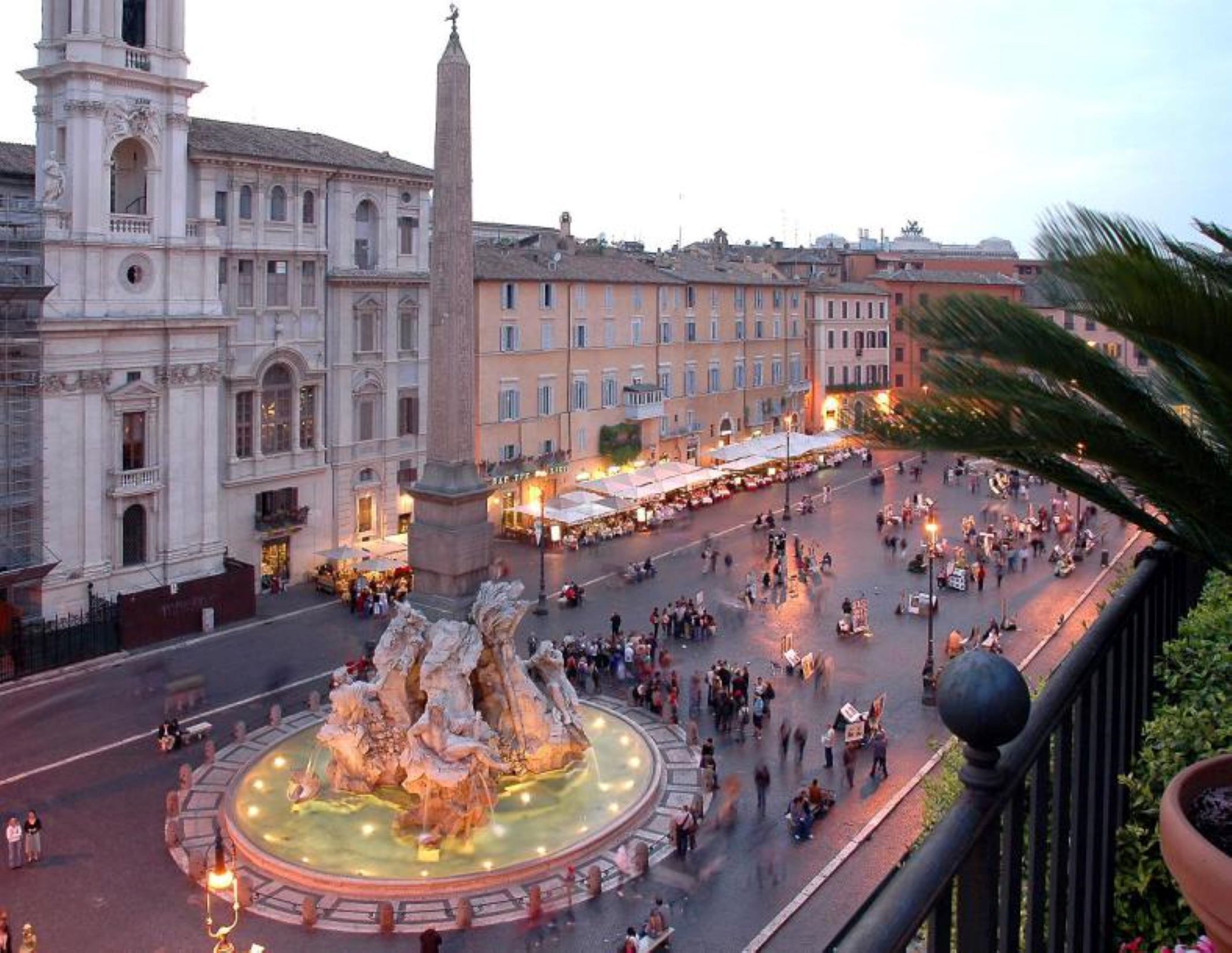 A public square with a central fountain, surrounded by historic buildings and a market area.