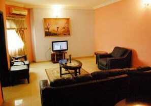 A living room with a sofa, a television, a small table, and a painting on the wall. - Room-somitel Hotels - Guest Room (Port Harcourt)