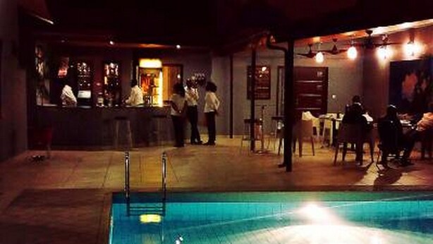 Un espace piscine intérieure doté d’un bar et d’un coin salon.