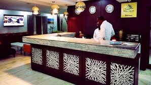 Un restaurant doté d’un comptoir central, de panneaux décoratifs sur les murs, de luminaires au plafond et d’un écran de télévision.