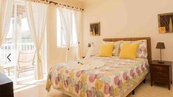 Un dormitorio con cama, mesita de noche, lámpara y una silla.