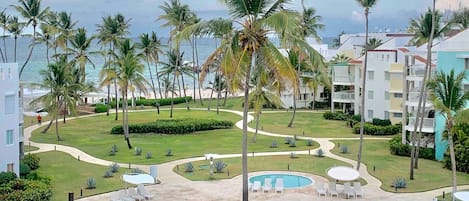 A resort with a pool area, palm trees, and a view of the ocean.