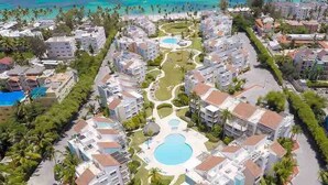 A resort with multiple buildings, a central pool, and a view of the ocean. - Ocean View, Private Beach, Playa Turquesa (Punta Cana)
