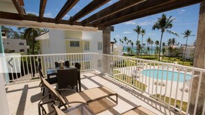 A covered outdoor area with a pool, lounge chairs, and a view of a beach and palm trees. - Ocean View, Private Beach, Playa Turquesa (Punta Cana)