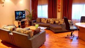 A living room with a television, sofas, a coffee table, and a desk with a chair. - Room-golden Tulip Port Harcourt-guest Ro (Port Harcourt)