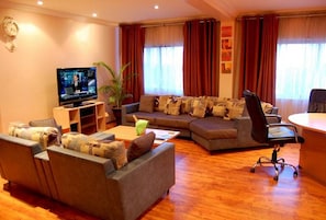 A living room with a television, sofas, a coffee table, and a desk with a chair.