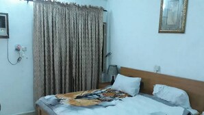Ein Schlafzimmer mit Bett, Vorhängen, Nachttisch, Lampe und einem Bilderrahmen an der Wand.