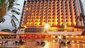Ein Hotel mit großzügigem Poolbereich, mehreren Balkonen und einem Gebäude mit Strohdach.