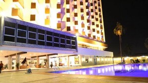Ein Hotel mit Pool, einer überdachten Passage und einem Gebäude mit einem gemusterten Fassadenbau.