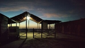 Un espacio al aire libre cubierto con estructura de techo metálico, piso de concreto y portón metálico.