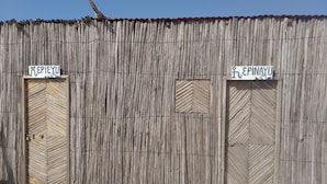 Un edificio de madera rústico con dos puertas, cada una señalizada con un letrero.
