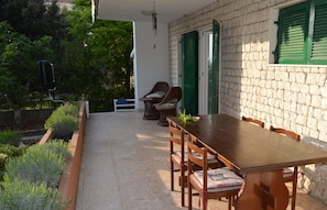 A patio with a wooden table and chairs, a stone wall, and a green shuttered door.
