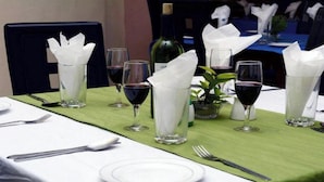 A dining table set with wine glasses, a bottle, and a small plant. - Room-christine Apartments-guest Room (Port Harcourt)