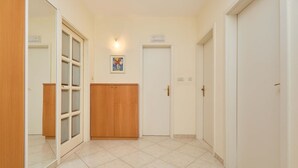 A hallway with a wooden wardrobe, a door with a handle, and a tiled floor. - Apartment Terra (Dubrovnik)