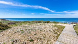 A wooden boardwalk leading to a coastal area with a clear view of the ocean. - 1907 Villa Alma (Alliste)