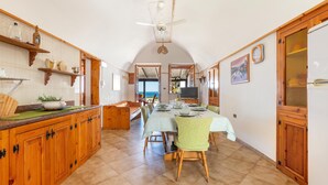 A spacious kitchen with wooden cabinets, a dining table set for four, and a view to the outside. - 1907 Villa Alma (Alliste)