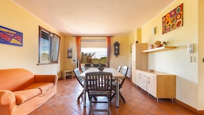 A dining area with a table and chairs, a sofa, a clock, and a window with curtains. - 1905 Villa Artas (Tuglie)
