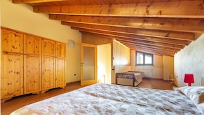 A bedroom with a large bed, wooden wardrobe, and a window with natural light. - 1905 Villa Artas (Tuglie)
