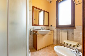 Une salle de bain équipée d’un lavabo, d’un miroir, de toilettes et d’une baignoire.