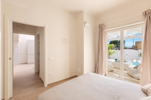 A bedroom with a large bed, a sliding glass door to a balcony, and a view of a swimming pool. - 1962 La Giada (Maruggio)