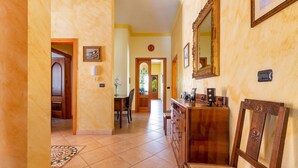 A hallway with a wooden bench, a mirror, and a door leading to another room. - 1929 Villa Simona (Ugento)