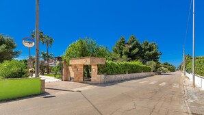 A quiet street with a small stone building, a green wall, and trees. - 1929 Villa Simona (Ugento)