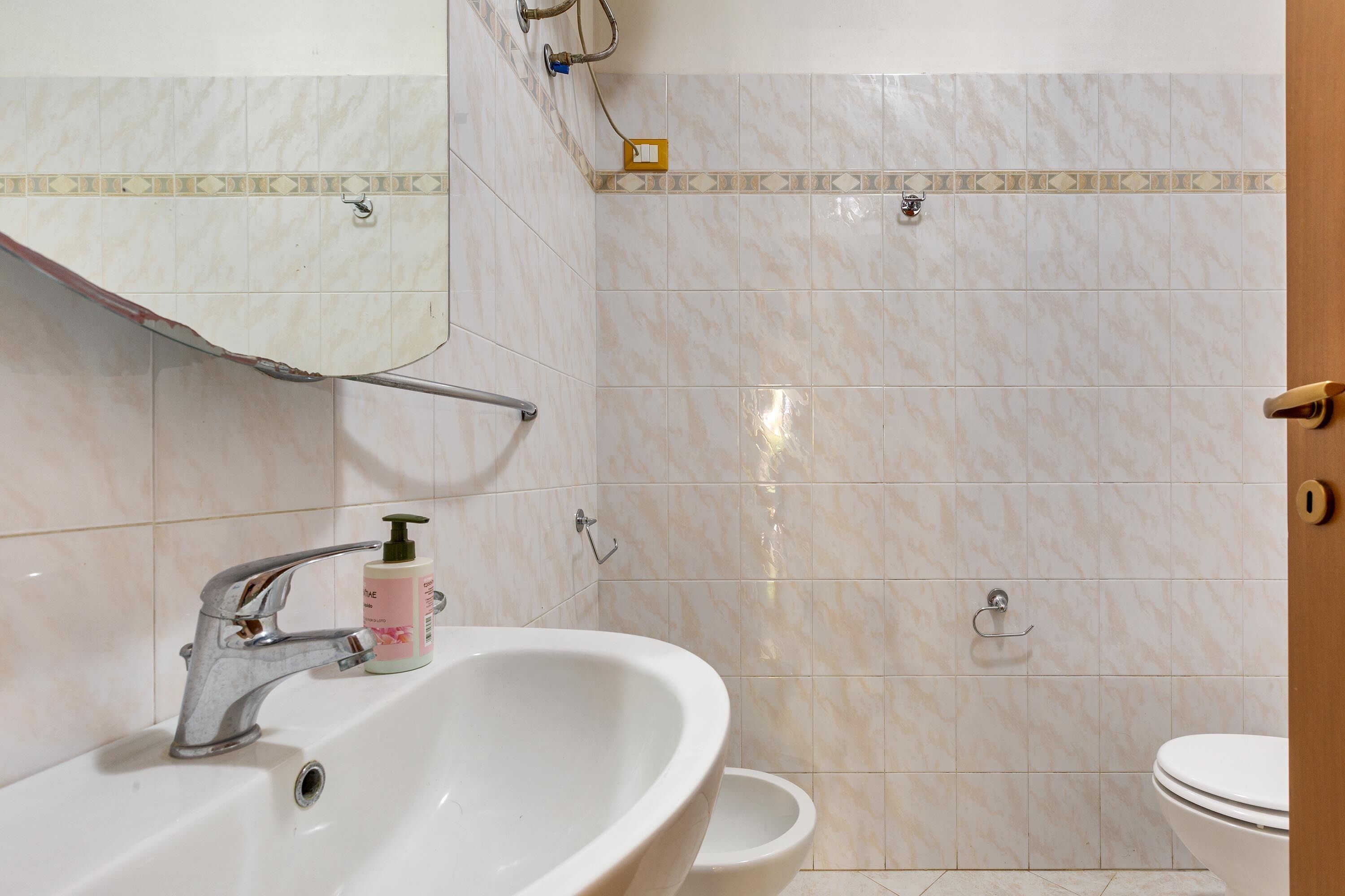 Et badeværelse med vask, spejl og toilet.