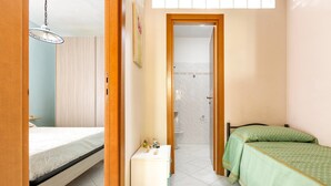 A bedroom with a bed, bedside table, and a small cabinet. - 1965 Villino dei Pini (Galatone)