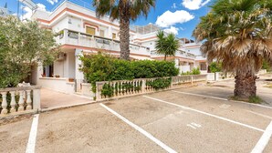 A residential building with a parking area, palm trees, and a clear sky. - 1965 Villino dei Pini (Galatone)