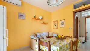 A dining area with a table set for four, a sofa, and a refrigerator. - 1965 Villino dei Pini (Galatone)